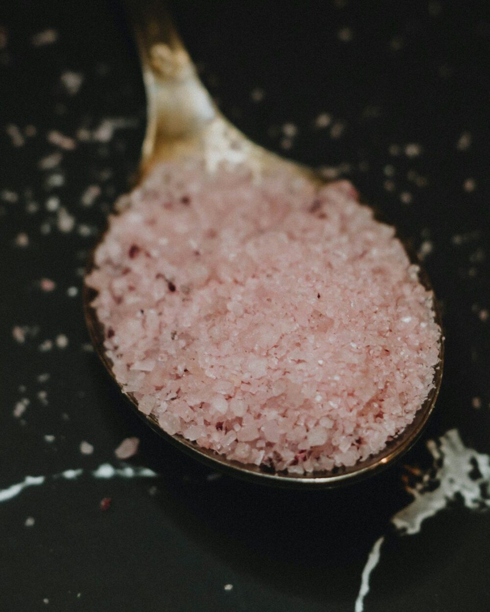 Pink halite heaped on a dark spoon
