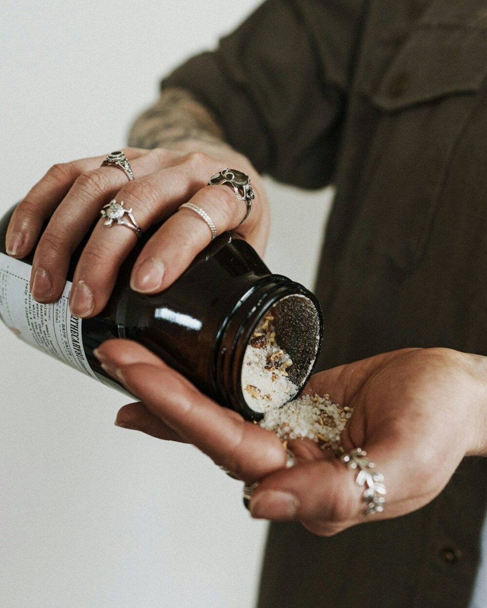 A hand tipping salts from an amber jar