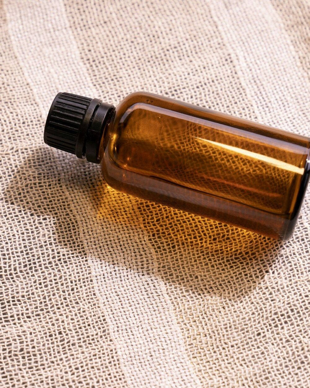 Amber bottle resting on woven linen