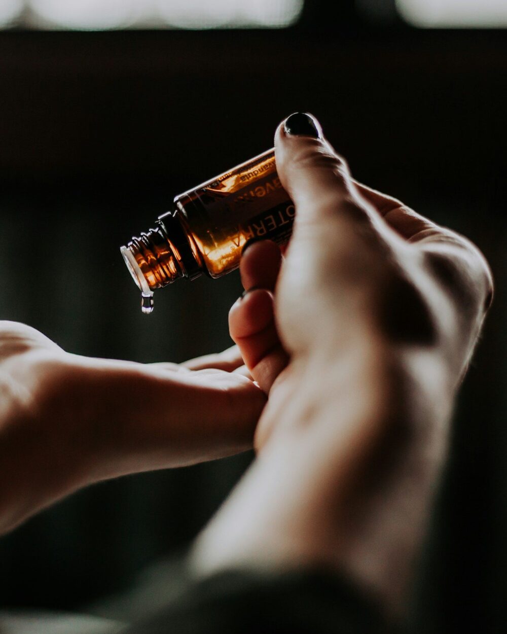 Hair oil poured from a dropper into a cupped hand